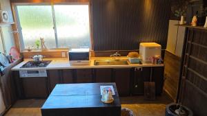 a kitchen with a sink and a counter with a laptop at ゲストハウス　竹亭 in Marugame