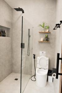 a bathroom with a toilet and a glass shower stall at Moringa Private Room in General Luna