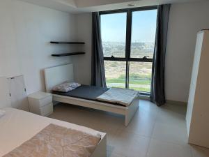 a bedroom with a bed and a large window at Pinnacle Row Panoramic 2BR Oasis in Muscat +28 photos