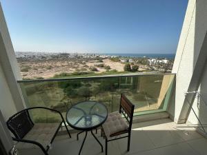 a balcony with a table and chairs and a view of the ocean at Pinnacle Row Panoramic 2BR Oasis in Muscat