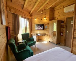 a bedroom with a bed and two chairs and a television at Sarı Köşk Hotel in Rize