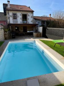 a large blue swimming pool in front of a house at A Casa da aldea de Iria in Padrón