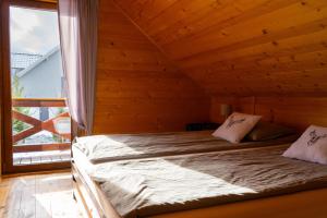 two beds in a wooden room with a window at Zielona Dolinka in Kostrzyca