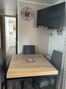 a wooden table with chairs and a television on a wall at Mobilhome 592 FUNPASS NON INCLUS in Gastes