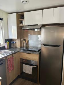 a kitchen with a stainless steel refrigerator and a sink at Mobilhome 592 FUNPASS NON INCLUS in Gastes