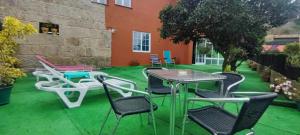 a patio with tables and chairs on a green lawn at Hospedaje Villa Blas in Redondela