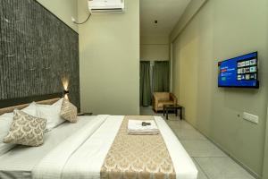 ein Schlafzimmer mit einem Bett und einem Fernseher an der Wand in der Unterkunft Zoho Suites in Kochi