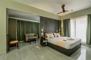 ein Schlafzimmer mit einem Kingsize-Bett und einem Sessel in der Unterkunft Zoho Suites in Kochi