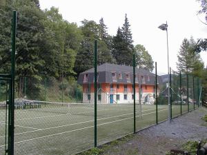 a tennis court with a house in the background at U Konupy in Ober Lindewiese