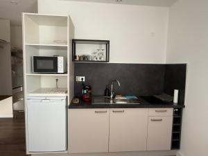 a white kitchen with a sink and a microwave at Le 6 by Montélimar in Montélimar