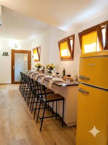 a long table with chairs and a yellow refrigerator at La Grotta Sardegna 5 Bedrooms each with a Private Ensuite Bathroom featuring a Hydromassage Shower Air Conditioning in Urzulei