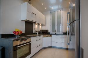 a kitchen with white cabinets and a stainless steel refrigerator at Appartement Vaste Horizon - LRA Cannes in Cannes