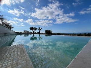 a swimming pool with a blue sky and clouds at Sunset Edge Villa - 77 Retreats in Għajn Tuffieħa