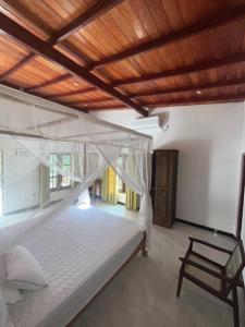 a bedroom with a white bed with a wooden ceiling at The villa Evans in Pitiduwa