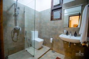 a bathroom with a shower and a toilet and a sink at Serene Lake View Resort in Anuradhapura +15 photos