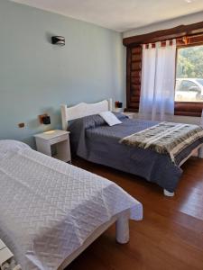 two beds in a hotel room with a window at Hosteria EL REFUGIO in Aluminé