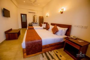 a hotel room with two beds and a television at Serene Lake View Resort in Anuradhapura