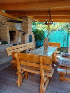 a wooden table and benches on a deck with a fireplace at Apartment Larion in Štúrovo
