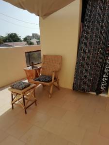 a chair and a stool on a balcony at Maison Manour Studio 4 personen in Mbour