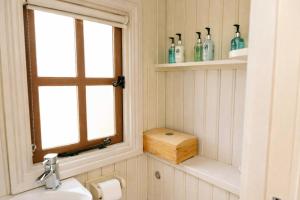 a bathroom with a sink and a window with bottles on shelves at Morndyke Shepherds Huts in Thirsk