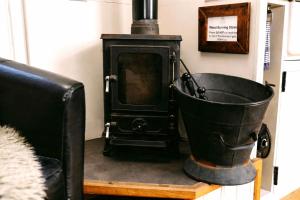 a black stove in a room with a bucket at Morndyke Shepherds Huts in Thirsk
