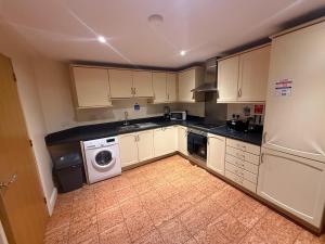 a kitchen with white cabinets and a washer and dryer at Comfort Arena in Colchester
