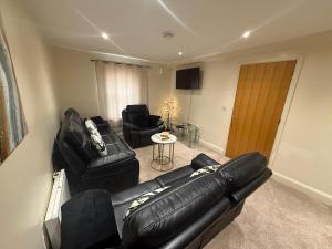 a living room with a black leather couch and chairs at Comfort Arena in Colchester