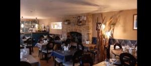 a restaurant with tables and chairs and a fireplace at Auberge de la Poterne in Moncontour