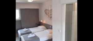 two beds in a small room with a shower at Auberge de la Poterne in Moncontour