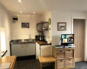 a kitchen with a sink and a counter with a television at Pier Cottage at Kames in Kames