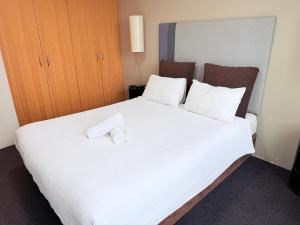 a hotel room with a large white bed with two pillows at 1 Bedroom Apartment In the heart of Parramatta CBD in Sydney +11 photos