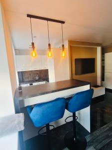 a kitchen with a bar and two blue chairs at G Apartments in Rēzekne