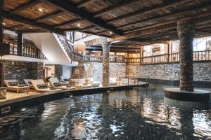 a swimming pool in a building with chairs and a building at Aïda Hôtel & Spa - "Adults Only" Relais & Châteaux in Crans-Montana
