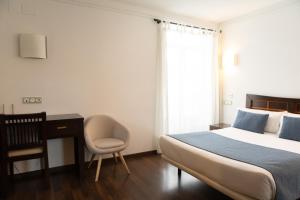 a bedroom with a bed and a desk and a chair at Hotel Rincón del Conde in León