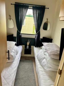 two beds in a room with a window at 6 berth static in Skegness in Chapel Saint Leonards