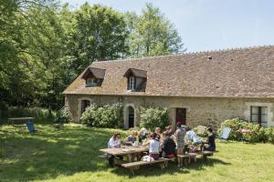 a group of people sitting at picnic tables in front of a building at La buanderie du château in Le Boulay