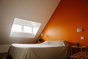 a bedroom with an orange wall with a bed and a window at La buanderie du château in Le Boulay