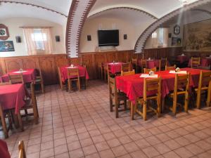 a restaurant with red tables and chairs and a flat screen tv at Penzion U Zeleného Stromu in Telnice
