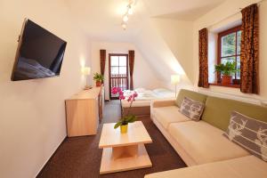 a living room with a couch and a tv at Wellness hotel Sauna in Malá Morávka
