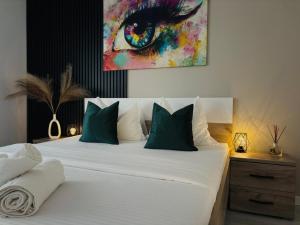 a bedroom with a large white bed with green pillows at Adam Residence in Oradea