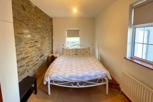 a bedroom with a bed and a stone wall at Beachfront Cottage - 3 bedrooms in Clogherhead