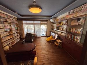 a library with bookshelves and a desk and a table at 離れの宿 かぶろの庭 離れの宿 KuRA in Matsukawa