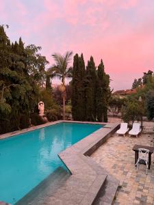 a swimming pool with a table and chairs and trees at Felina place by shuli in Ganne Yoẖanan
