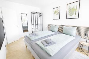 two beds in a room with white walls at Larooms Merseburg - Apartment CS01 - 3 Zimmer, 7 Betten, 2 Bäder, 2 Parkplätze, Balkon & Aufzug in Merseburg