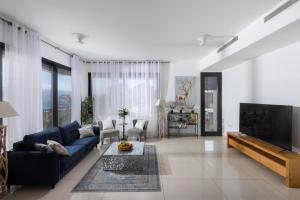 a living room with a blue couch and a tv at הבית על ההר - Ella Sun in Eilat