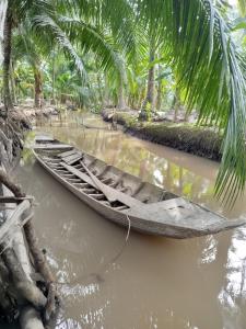 a boat in the water next to a palm tree at Green Coconut Island in Ấp Thới Hòa (3)