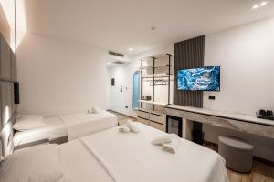 a room with three beds and a tv on a wall at Hotel Resol 2 in Ksamil