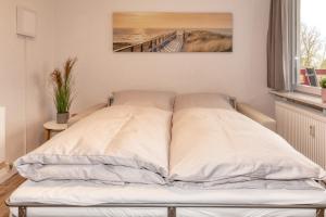 a bed in a bedroom with a painting on the wall at Terrassenhaus, FeWo 45 in Duhnen