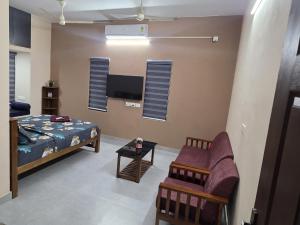 a room with a bed and a chair and a tv at Crystal Homestay in Trivandrum