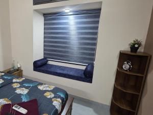 a bedroom with a window with a blue blind at Crystal Homestay in Trivandrum